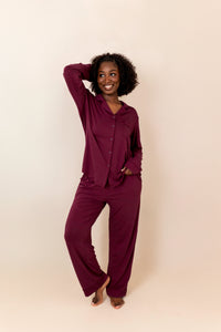 Woman wearing a burgundy pajama set against a plain background