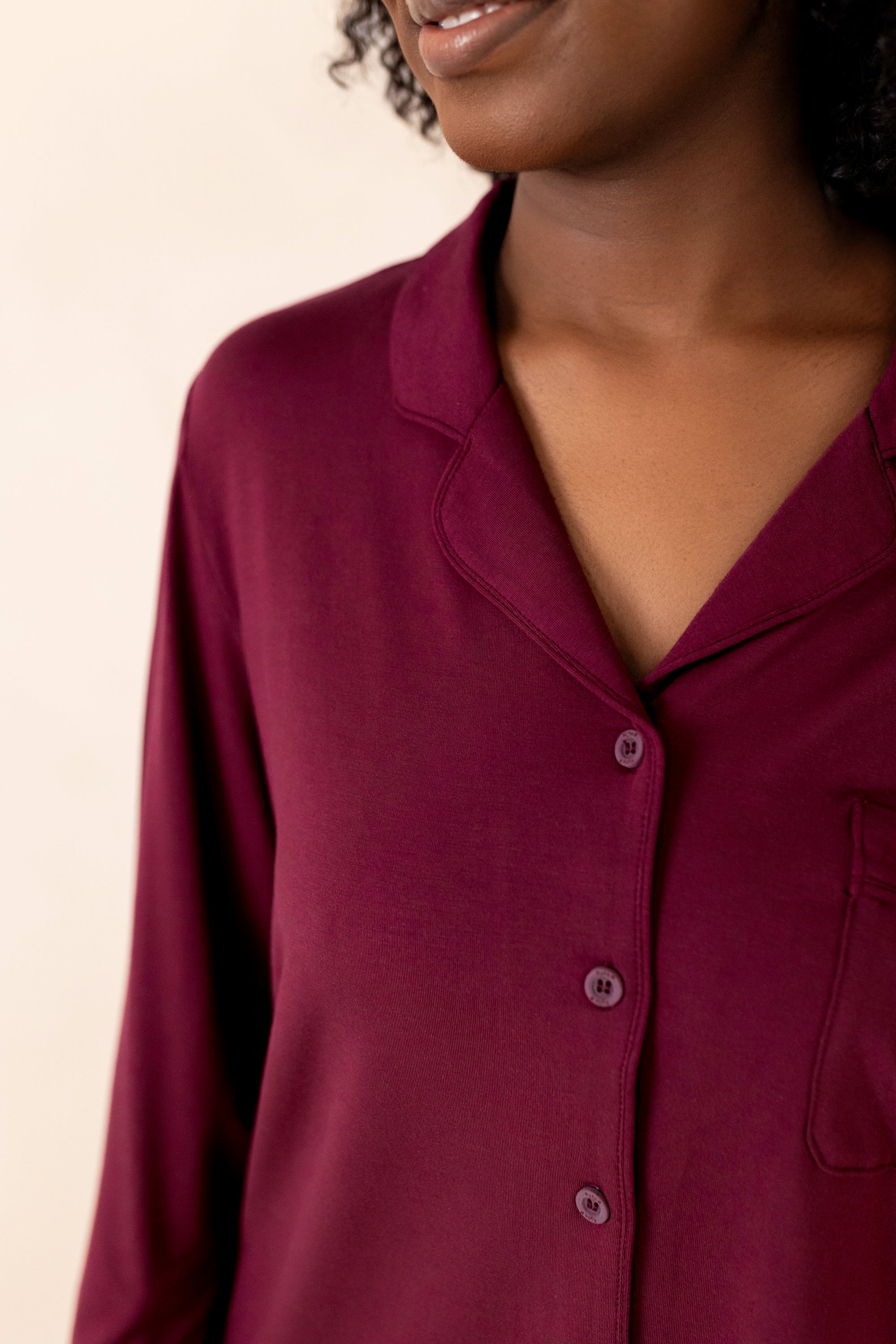 Close-up of a person wearing a burgundy shirt against a neutral background
---PJ 2