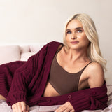 Woman wearing a burgundy cardigan over a brown bralette on a light-colored background