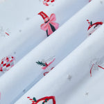 A repeating, all-over print featuring: a bottle of sparkling wine with pink packaging and a pink bow; pink bubbly in a coupe glass with a red bow tied around the stem and garnished with a sprig of rosemary and red berries; a pair of pink sparklers; a Santa Claus mug with a candy cane straw and a holly leaf; a pink-and-silver disco ball, and various metallic silver sparkles over a pale blue background color