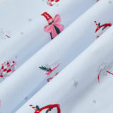 A repeating, all-over print featuring: a bottle of sparkling wine with pink packaging and a pink bow; pink bubbly in a coupe glass with a red bow tied around the stem and garnished with a sprig of rosemary and red berries; a pair of pink sparklers; a Santa Claus mug with a candy cane straw and a holly leaf; a pink-and-silver disco ball, and various metallic silver sparkles over a pale blue background color