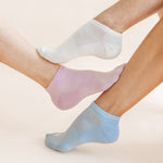 Three low-cut ankle socks in white, light pink, and light blue, shown on feet against a soft beige background.