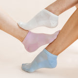 Three low-cut ankle socks in white, light pink, and light blue, shown on feet against a soft beige background.