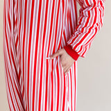 Woman showcasing the pockets on Long Sleeve Adult Sleep Bag Walker in red and white Peppermint Stripe print on a beige background