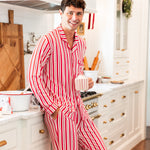 Modal wearing Men's Long Sleeve Pajama Set in red and white Peppermint Stripes print standing in a kitchen while holding a cup
::: Model is 6'1" wearing size M ///