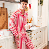 Modal wearing Men's Long Sleeve Pajama Set in red and white Peppermint Stripes print standing in a kitchen while holding a cup
::: Model is 6'1" wearing size M ///