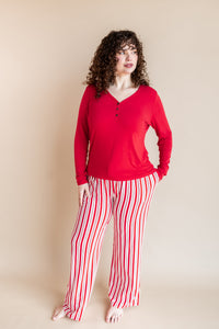 Modal wearing Women's Lounge Pants in red and white Peppermint Stripes print under a red T-shirt on a beige background
