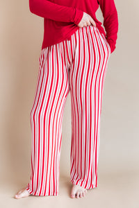Modal wearing Women's Lounge Pants in red and white Peppermint Stripes print under a red T-shirt on a beige background