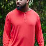 Model standing outside while wearing the Men's Long Sleeve Henley Top in Cardinal