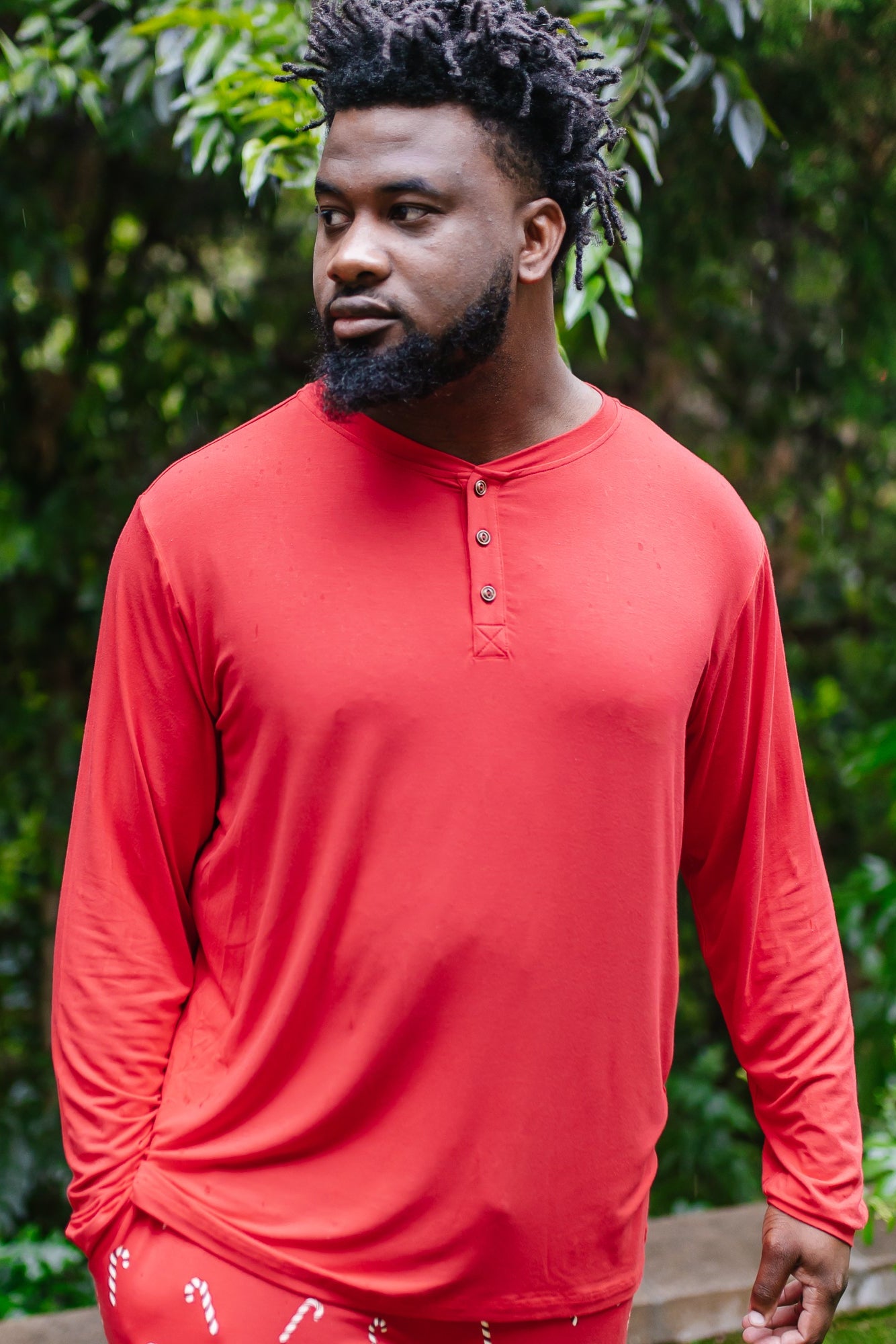 Model standing outside while wearing the Men's Long Sleeve Henley Top in Cardinal