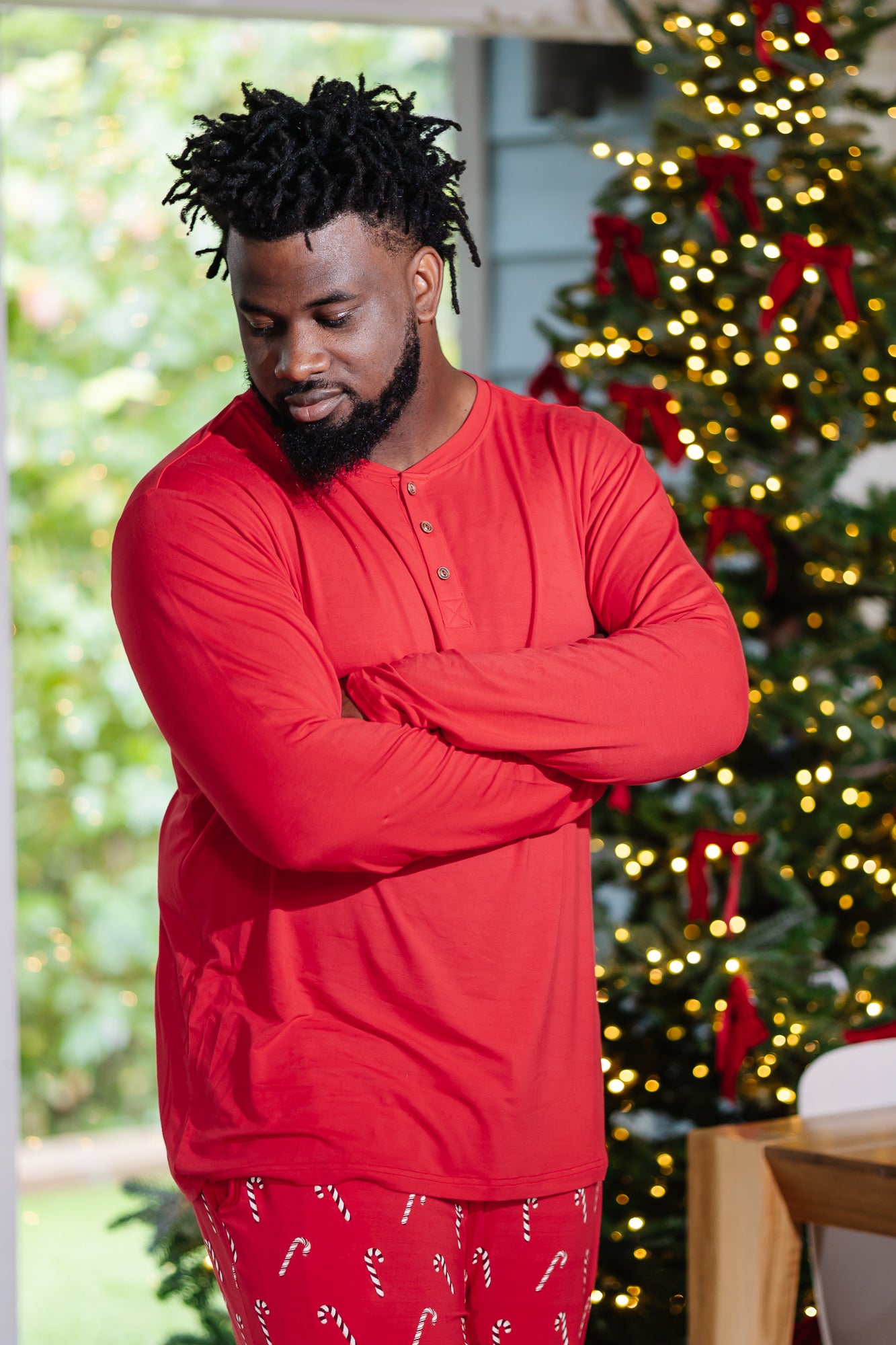 Model with arms crossed across chest and wearing the Men's Long Sleeve Henley Top in Cardinal