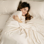 Female laying in bed on the Bamboo Sateen Sheet Set in Champagne