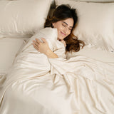 Female laying in bed on the Bamboo Sateen Sheet Set in Champagne