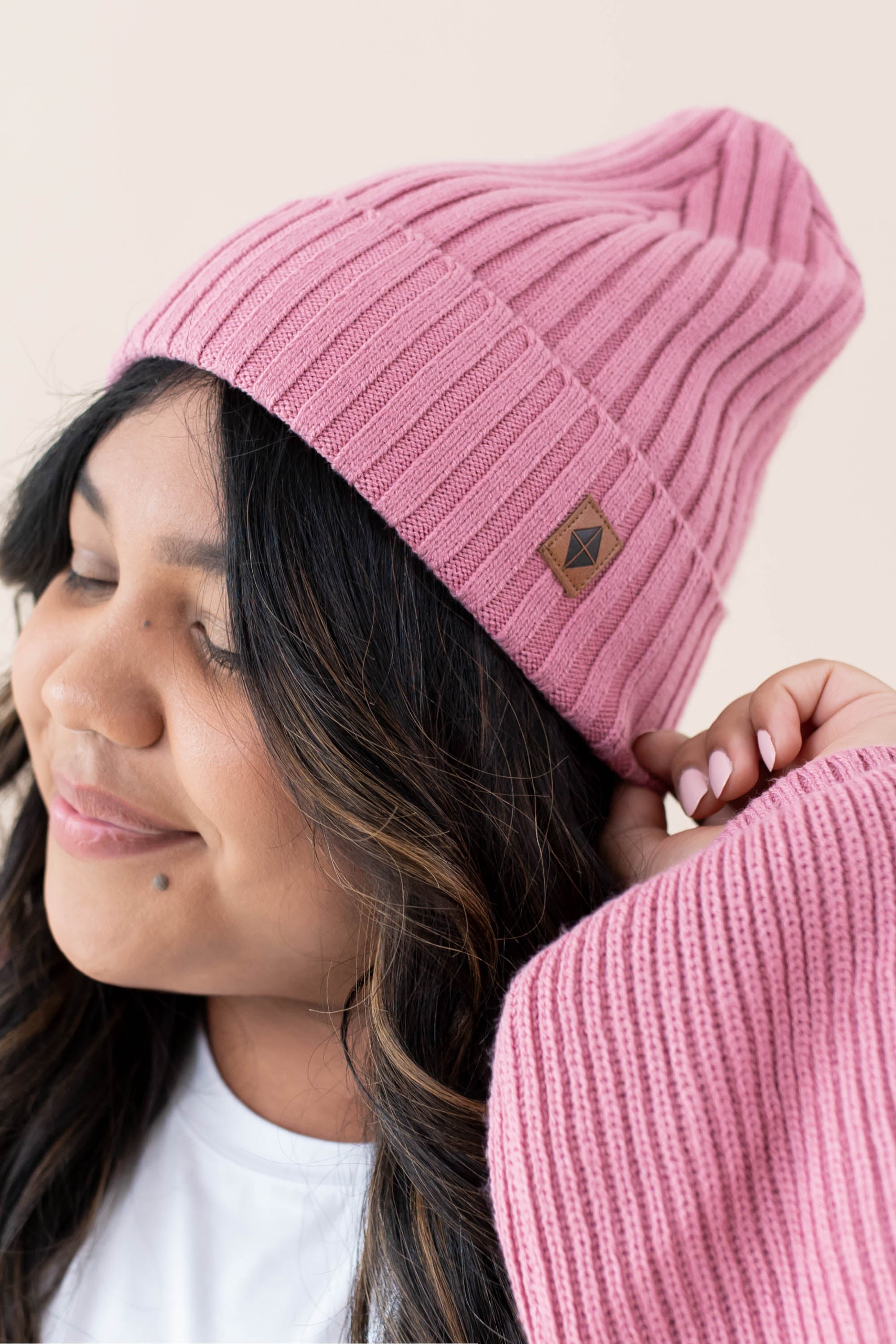 Model wearing the Chunky Knit Adult Ribbed Beanie in Apple Blossom with the Kyte Baby Leather Logo visibile