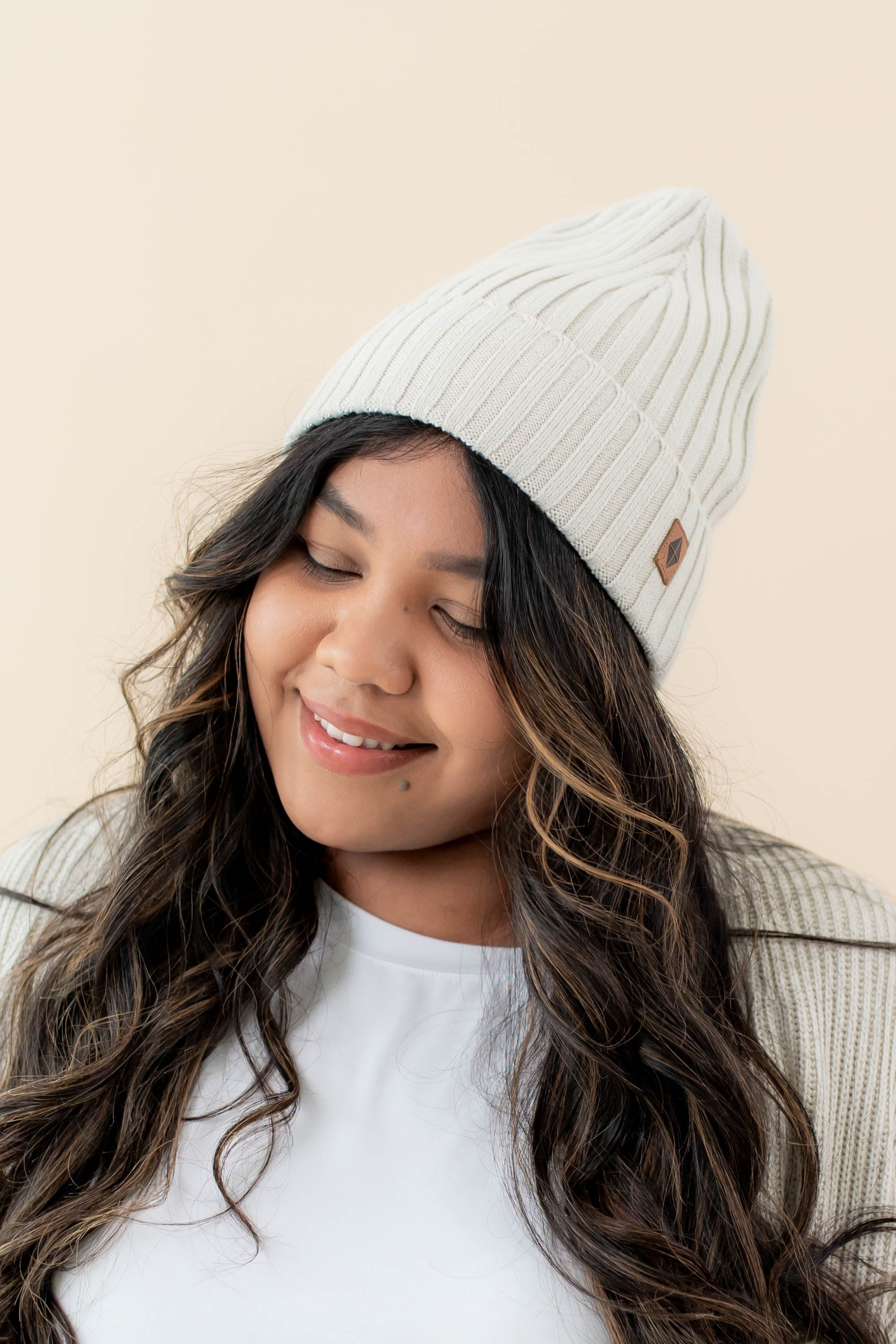 Smiling model wearing the Chunky Knit Adult Ribbed Beanie in Oat