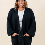 Female modeling the Chunky Knit Women's Oversized Cardigan in Midnight wearing a white shirt, black pants and Midnight Beanie