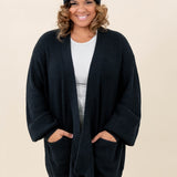 Female modeling the Chunky Knit Women's Oversized Cardigan in Midnight wearing a white shirt, black pants and Midnight Beanie
