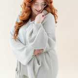 Female wearing the Chunky Knit Women's Oversized Cardigan in Oat paired with a white shirt and white pants