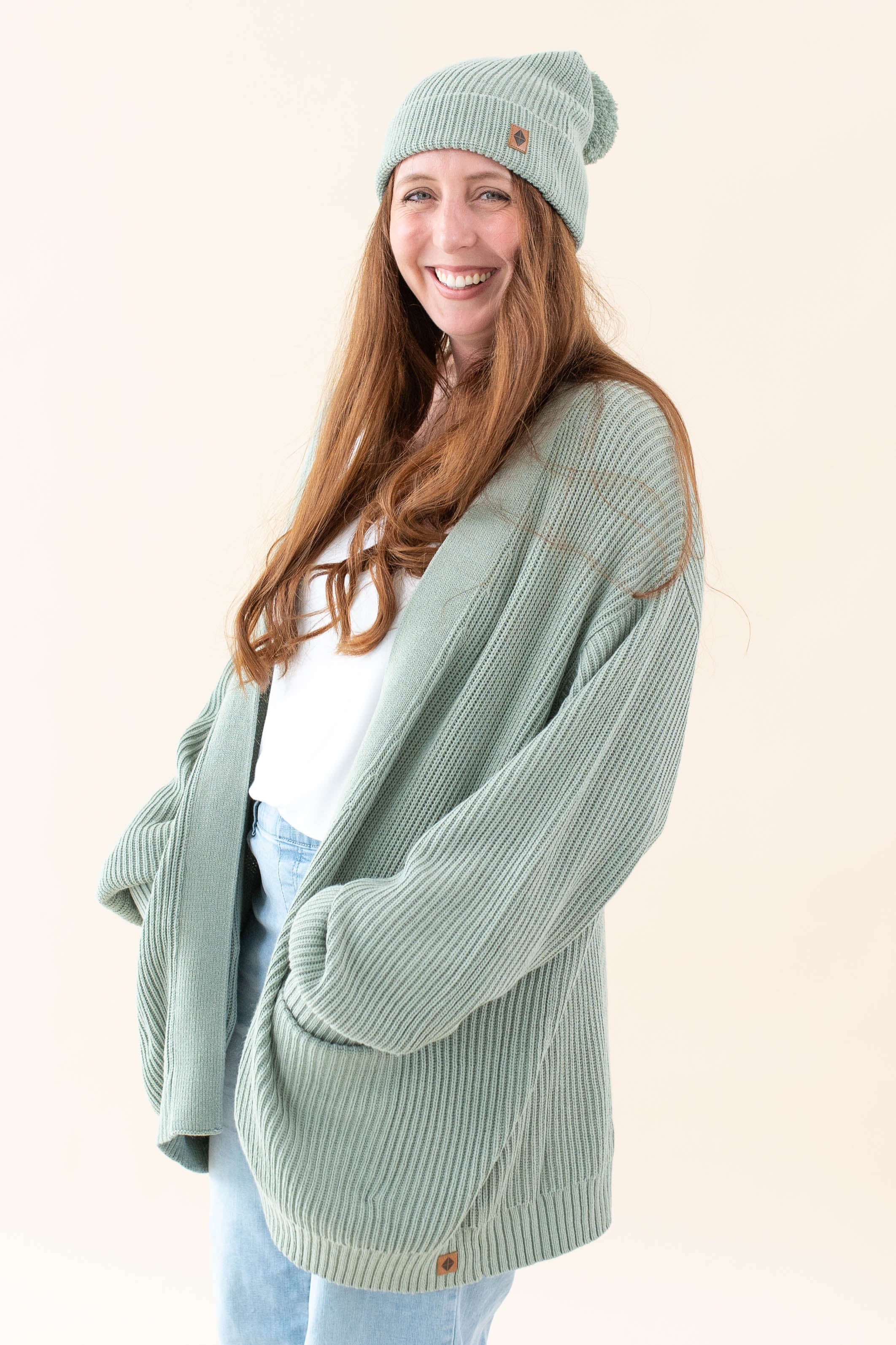 Model wearing the Thyme Chunky Knit Women's Oversized Cardigan paired with a Thyme Beanie, white shirt and light wash jeans