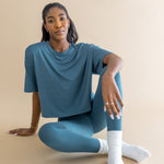 Woman wearing a blue outfit and white scrunch socks sitting on a beige background