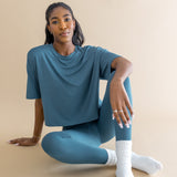Woman wearing a blue outfit and white scrunch socks sitting on a beige background