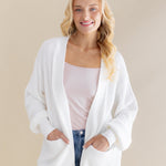 Female standing wearing the Chunky Knit Women's Oversized Cardigan in Cloud with both hands in the pocket