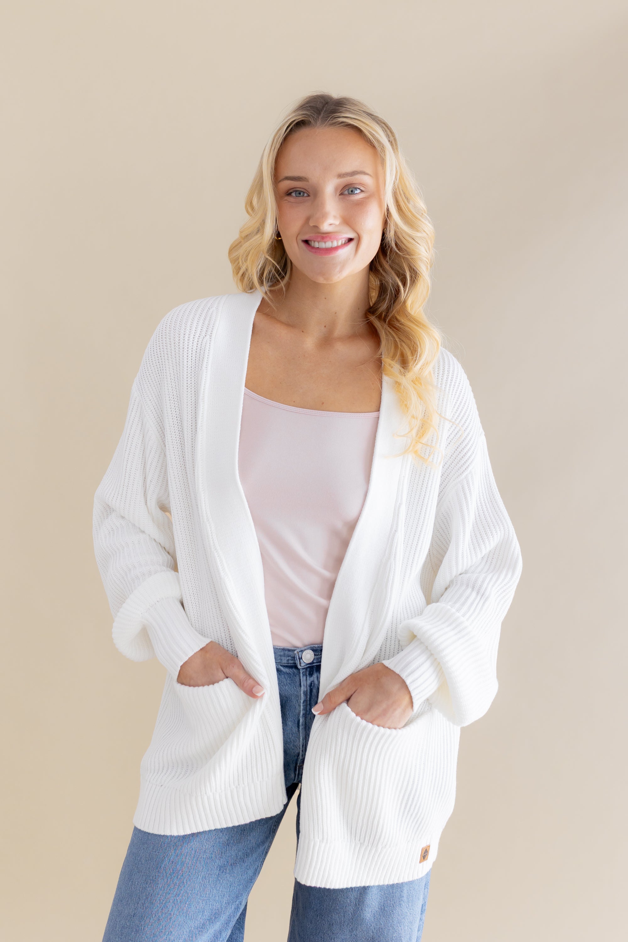 Female standing wearing the Chunky Knit Women's Oversized Cardigan in Cloud with both hands in the pocket