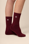 Burgundy socks with a logo worn by a person on a beige background