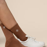 Brown socks worn with white sneakers on a beige background