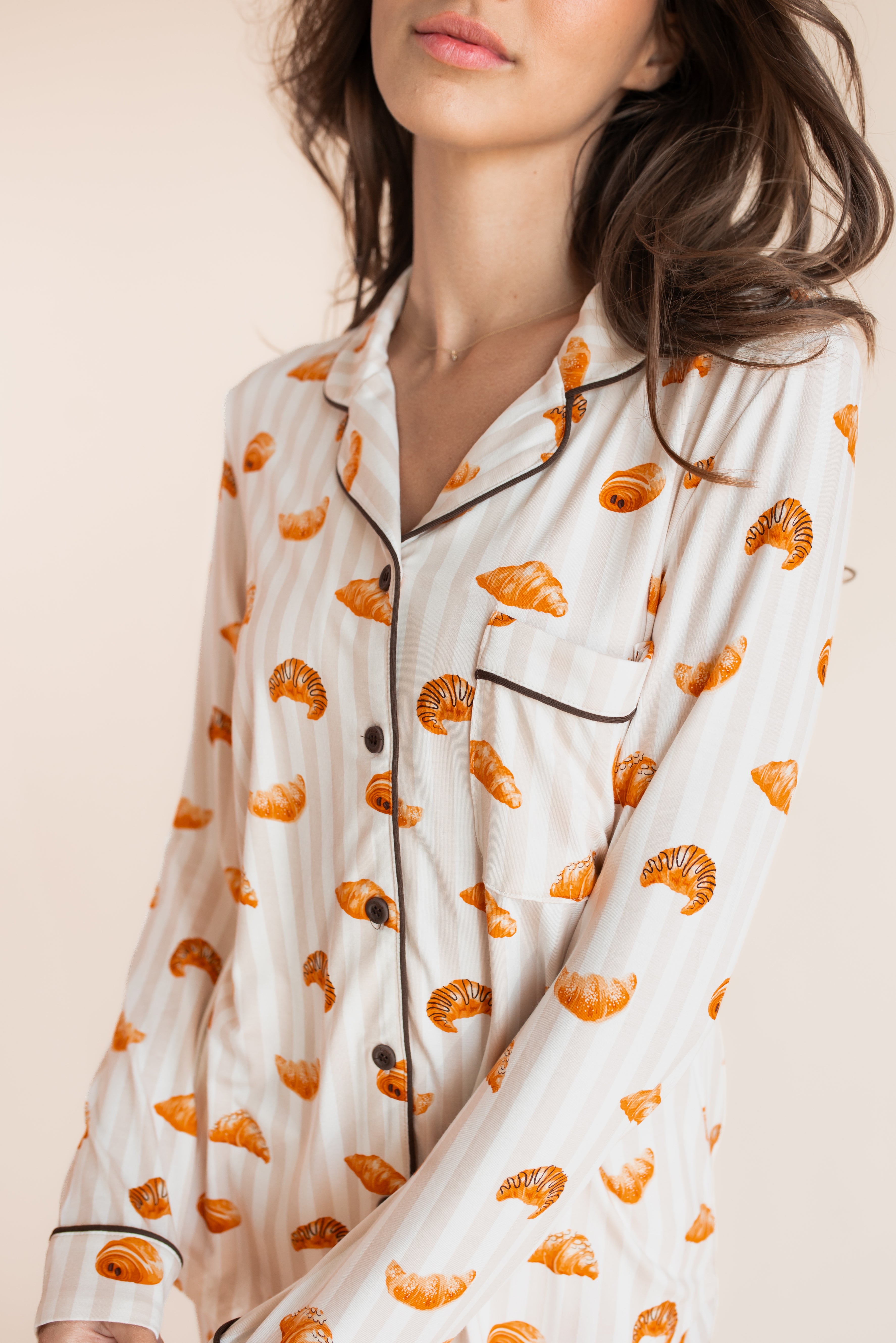 Close up of Model wearing Long-Sleeved Women's Pajama Set in Croissant print on a beige background
---PJ 2