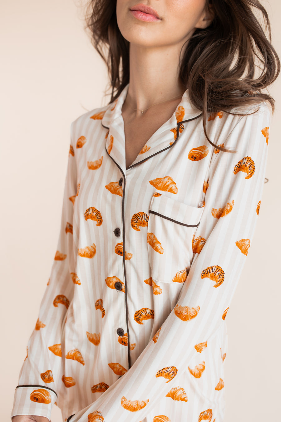 Close up of Model wearing Long-Sleeved Women's Pajama Set in Croissant print on a beige background