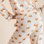 Model showcasing backside of Long-Sleeved Women's Pajama Set in Croissant print on a beige background