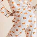 Model showcasing backside of Long-Sleeved Women's Pajama Set in Croissant print on a beige background