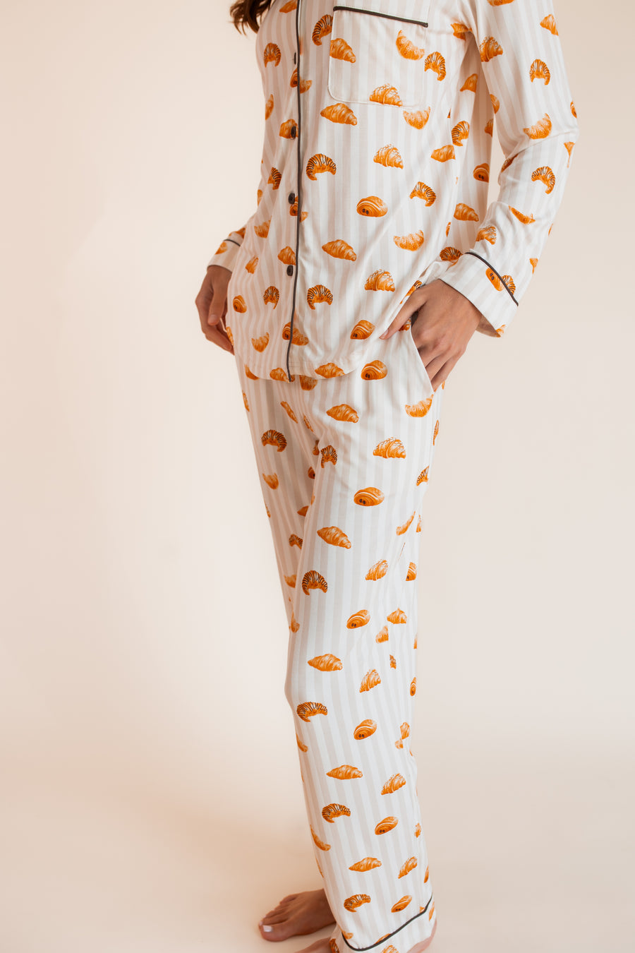 Model wearing Long-Sleeved Women's Pajama Set in Croissant print with pockets on a beige background