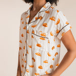 Close up of Model wearing Women's Short Sleeve Cropped Pajama Set in Croissant print on a beige background