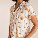 Close up of Model wearing Women's Short Sleeve Cropped Pajama Set in Croissant print on a beige background