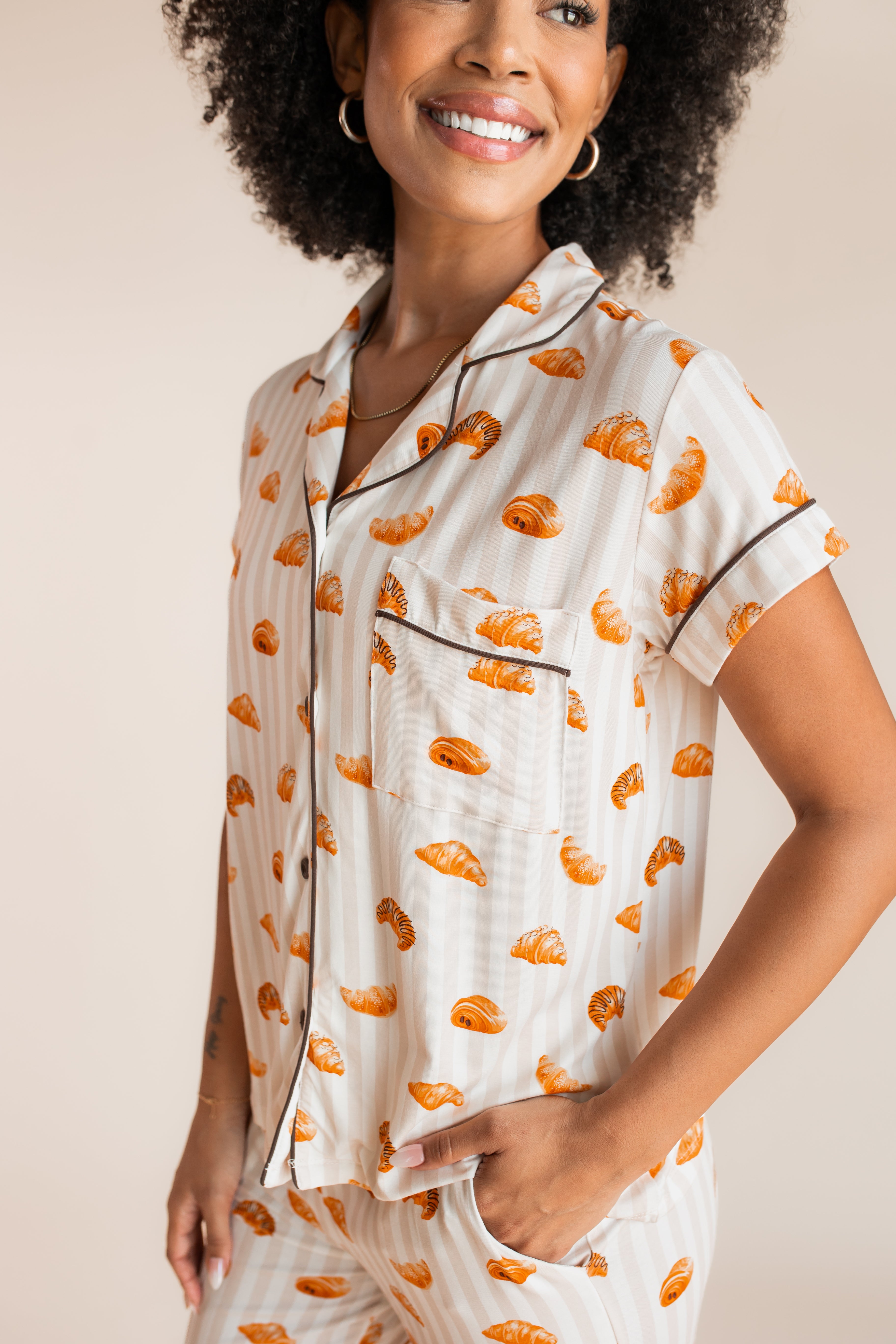 Close up of Model wearing Women's Short Sleeve Cropped Pajama Set in Croissant print on a beige background