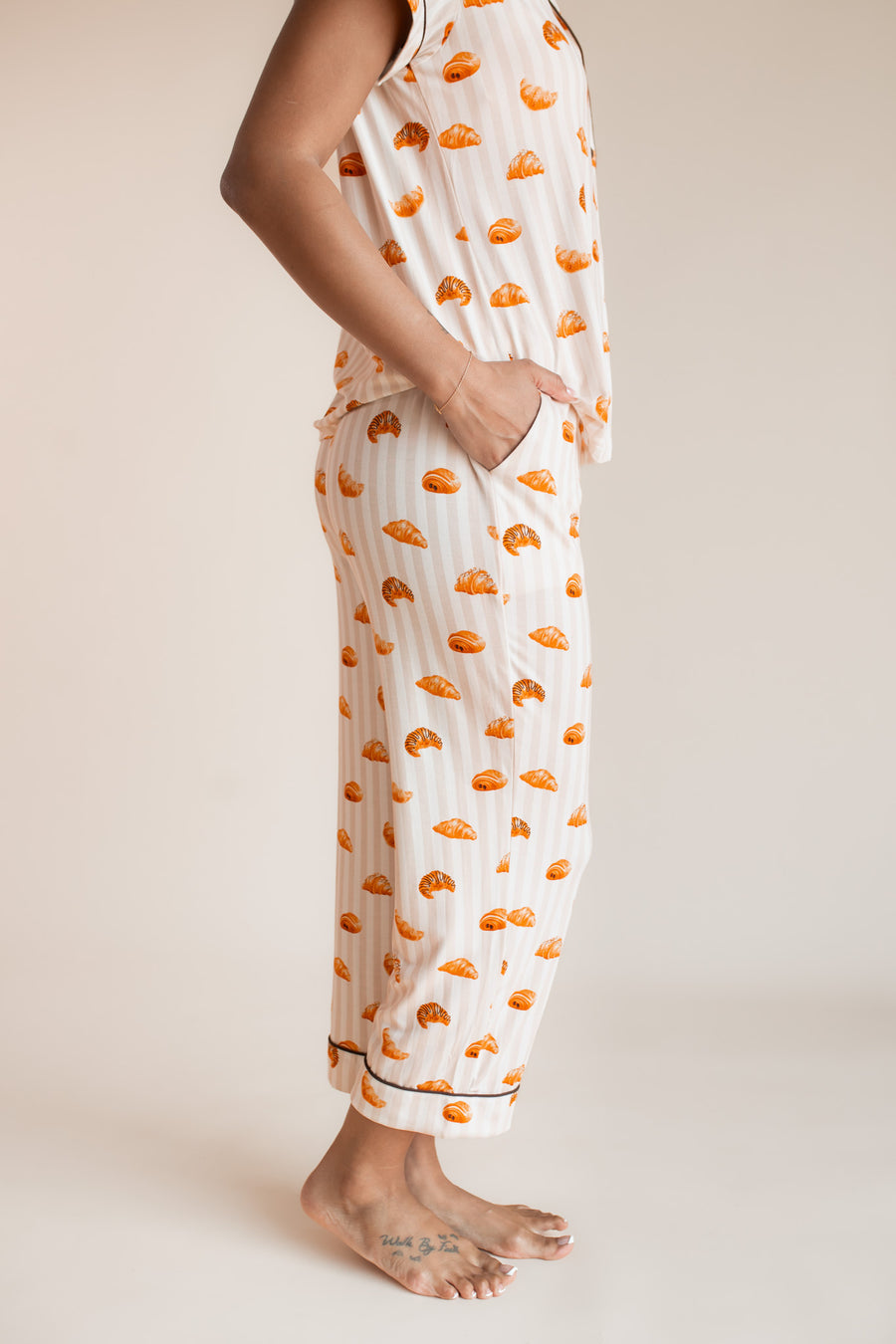 Model showcasing the pockets on Women's Short Sleeve Cropped Pajama Set in Croissant print on a beige background