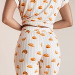 Model showcasing the backside of Women's Short Sleeve Cropped Pajama Set in Croissant print on a beige background