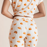 Model showcasing the backside of Women's Short Sleeve Cropped Pajama Set in Croissant print on a beige background