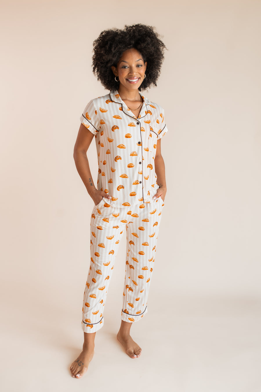 Model posing in Women's Short Sleeve Cropped Pajama Set in Croissant print on a beige background