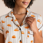 Model showcasing the collar on Women's Short Sleeve Cropped Pajama Set in Croissant print with brown trim on a beige background
---PJ 2
