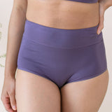 Woman wearing a purple scoop neck bra and high-waisted underwear set on a light background