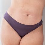 Woman in cheekini underwear and matching bralette in a deep purple color