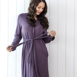 Woman wearing a purple robe against a white wooden panel background