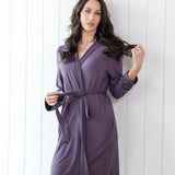 Woman wearing a purple robe against a white wooden panel background
