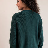 Modal showcasing back side of Chunky Knit Cropped Cardigan in cypress over blue jeans on a beige background