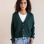 Modal wearing Chunky Knit Cropped Cardigan in cypress over white t-shirt and blue jeans on a beige background