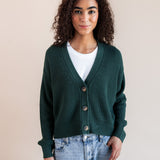 Modal wearing Chunky Knit Cropped Cardigan in cypress over white t-shirt and blue jeans on a beige background