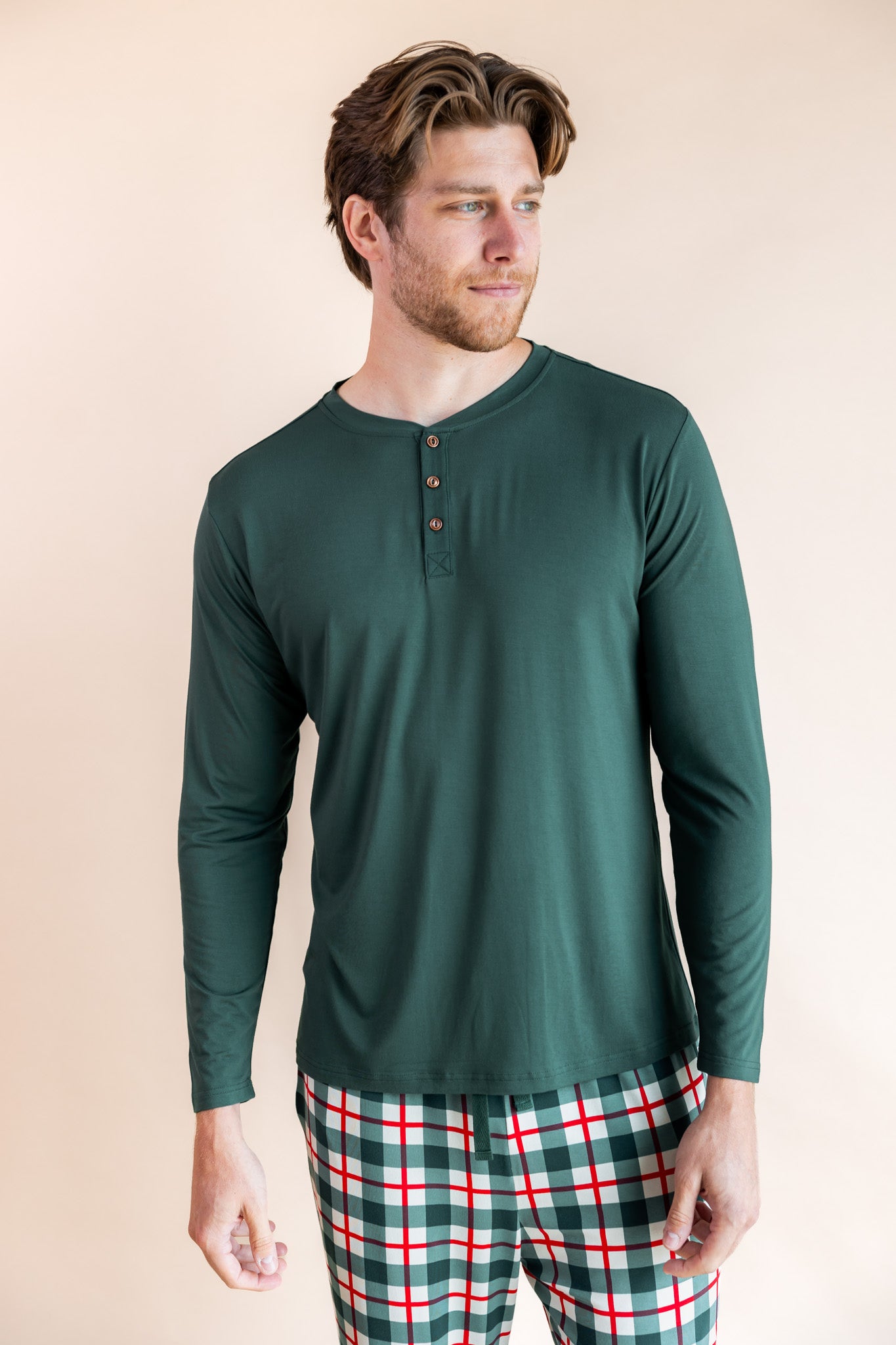 Man looking to the side wearing a long sleeve henley top in cypress and lounge pants in holiday plaid
::: Model is 6'3" wearing size L ///